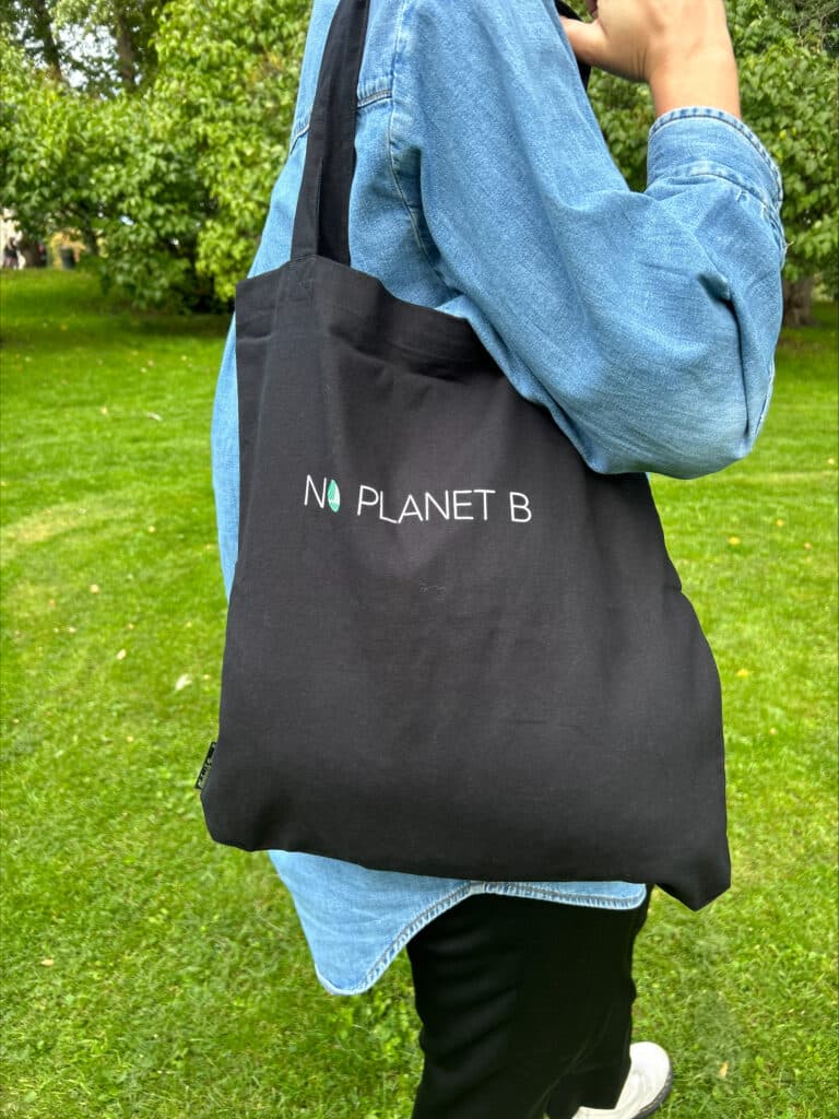 Svart svanemerket handlenett med "No Planet B" tekst hengenende over skulderen
